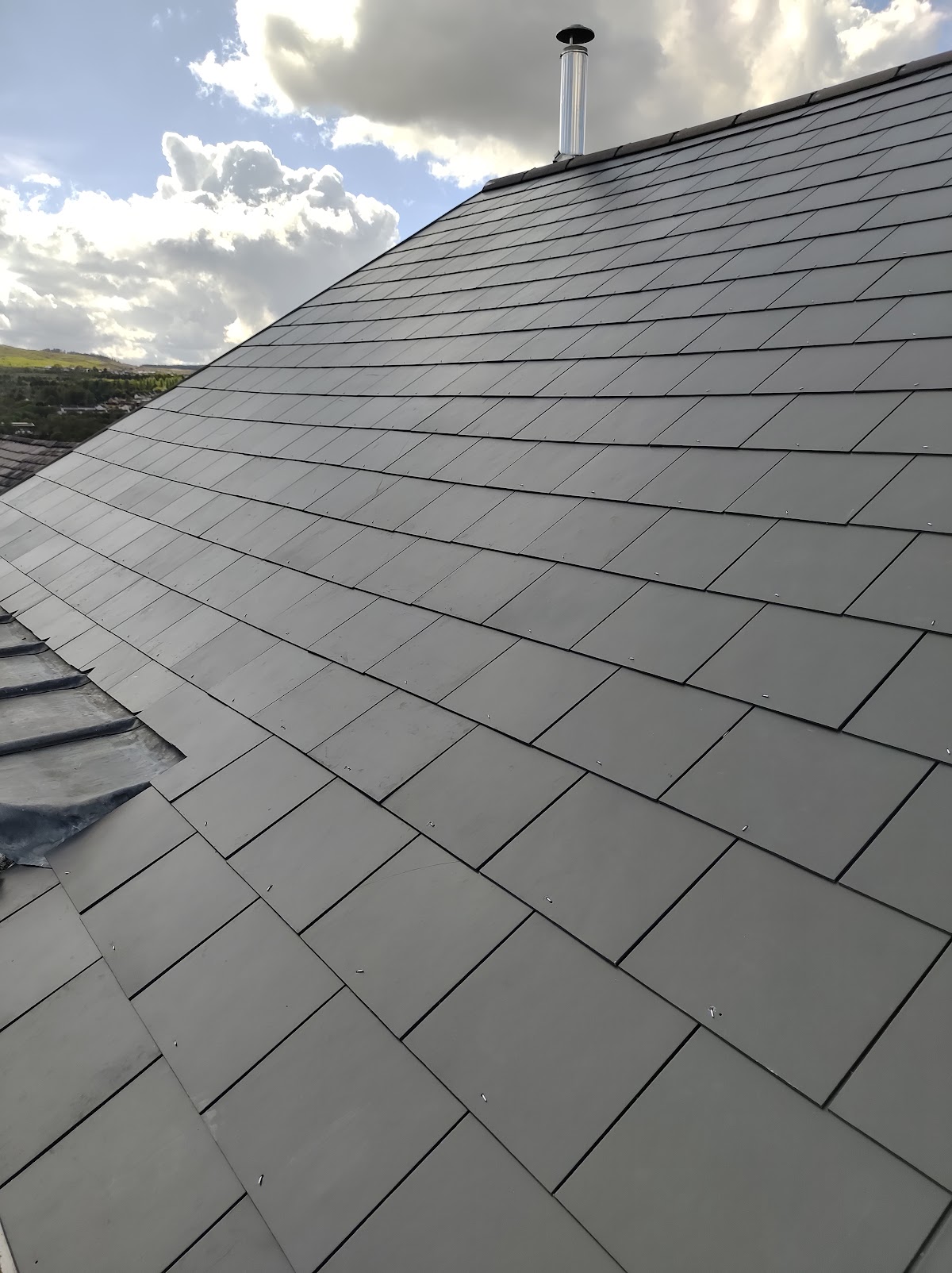 New natural slate roof with chimney flue, valley view behind