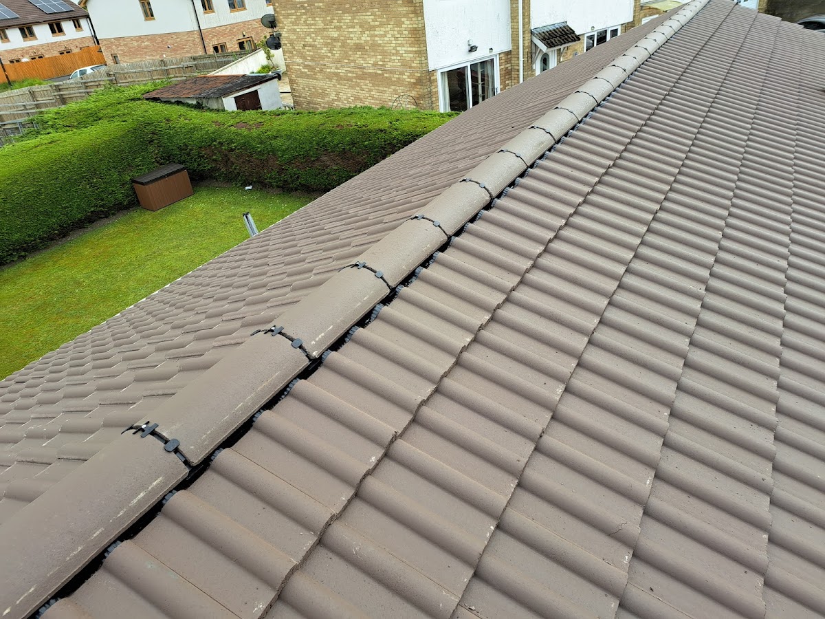 New brown concrete tiled roof with ridge tiles and garden behind