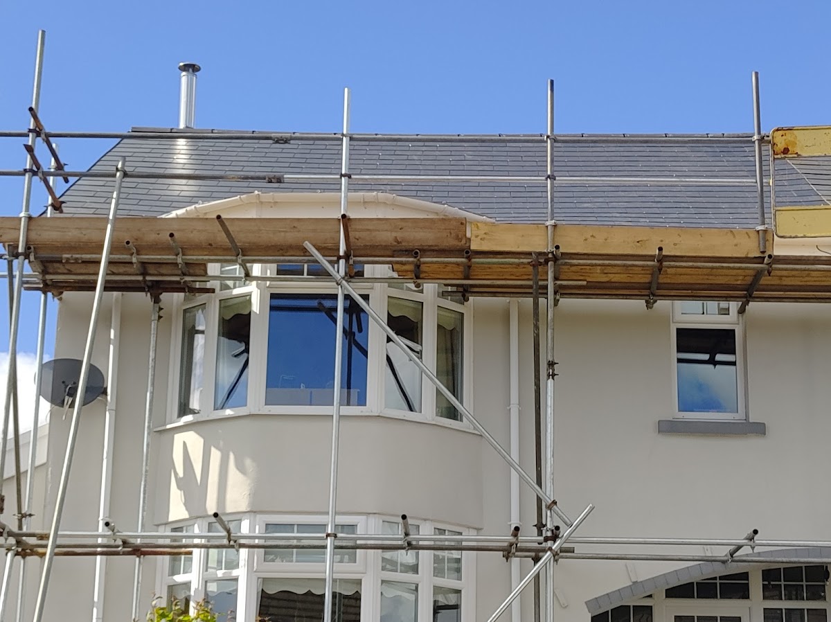Scaffolded house with a new slate roof above a bay window